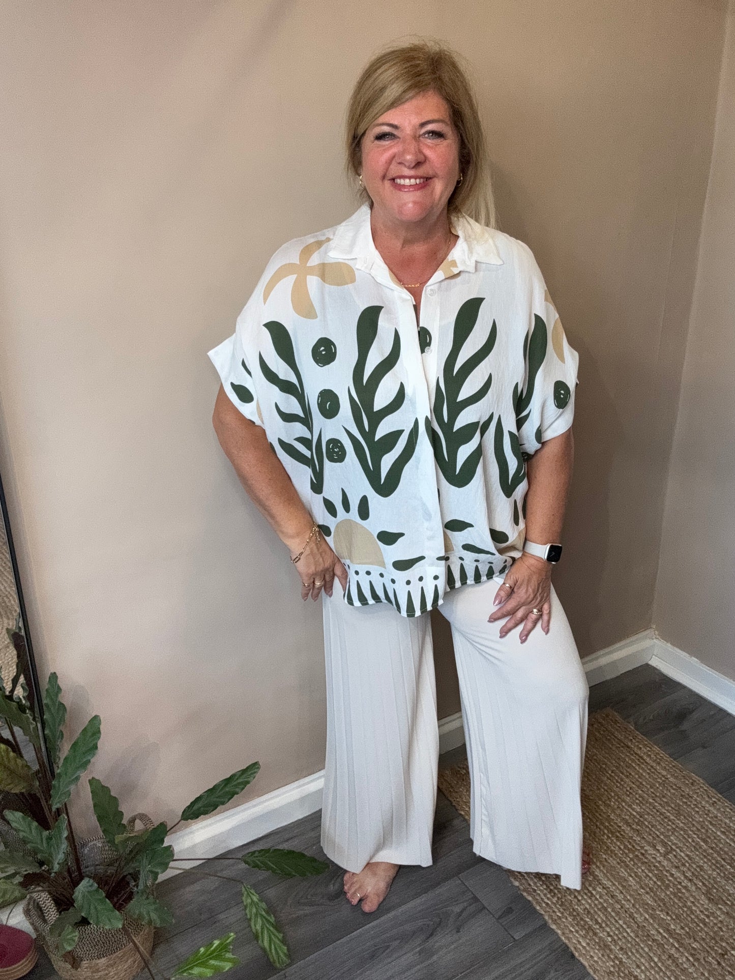Woman wearing a white outfit with green leaf patterns indoors.