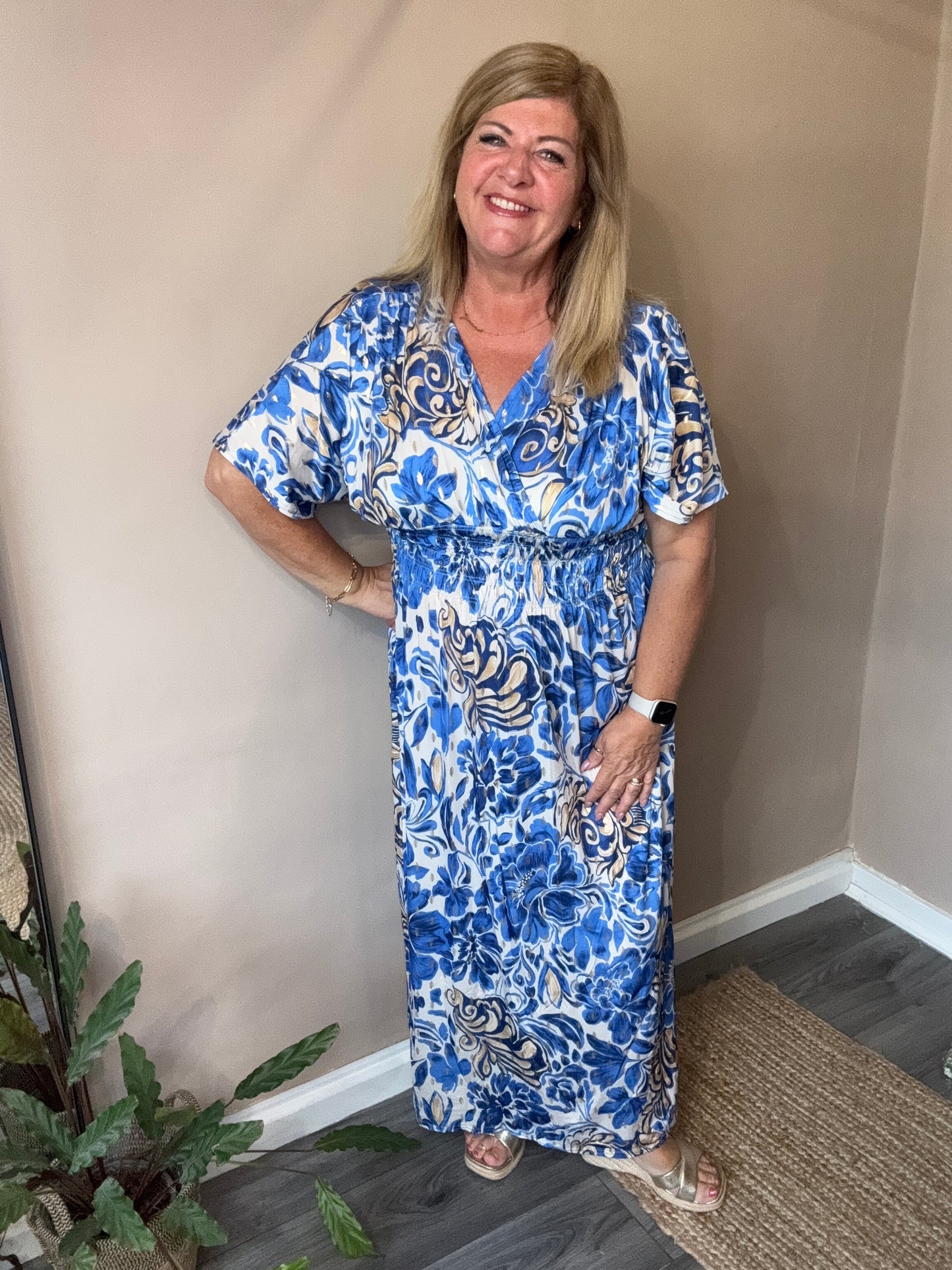 Woman in a blue and white patterned dress standing indoors.