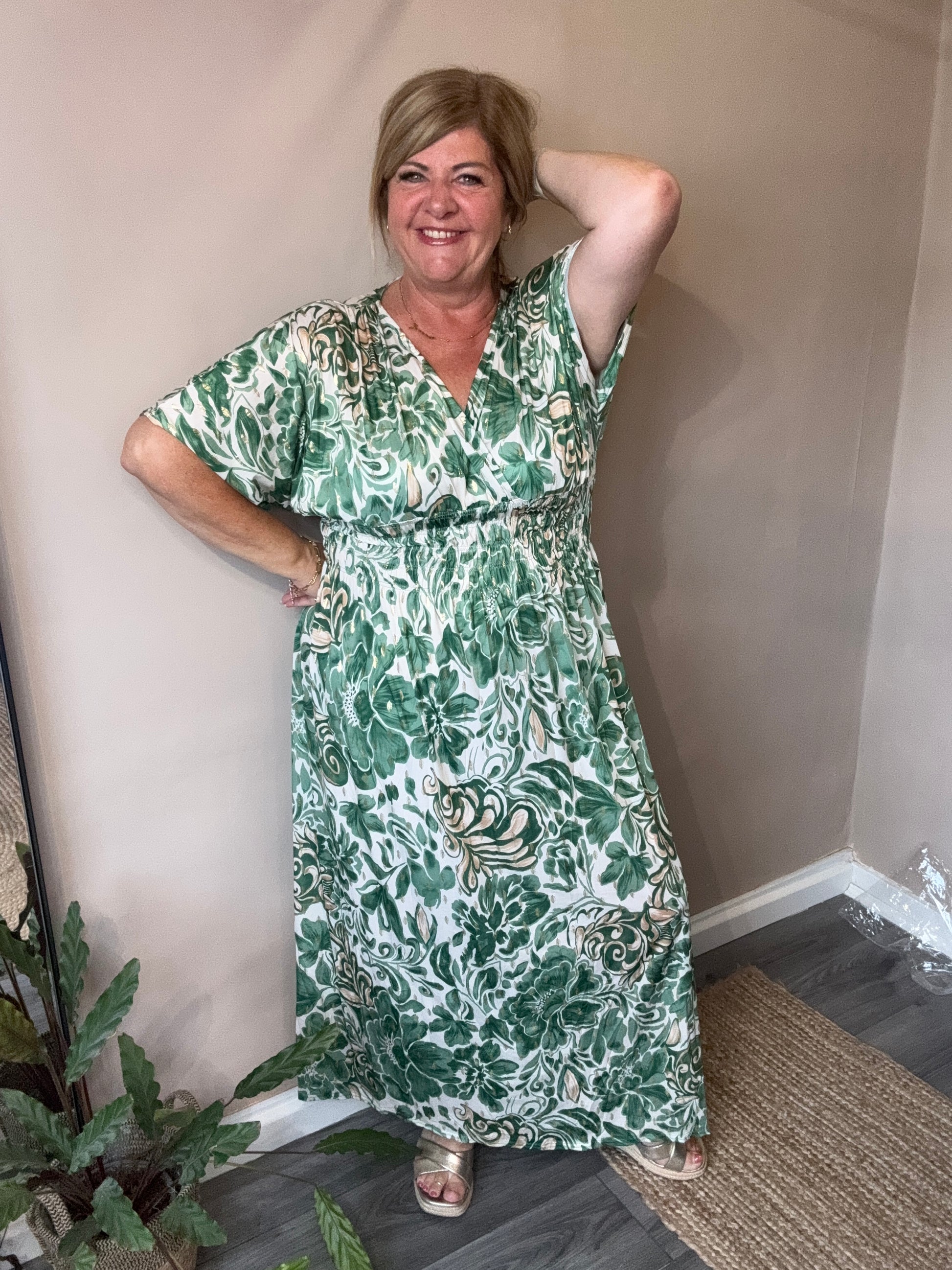 Woman wearing a green floral dress lying on a couch indoors.